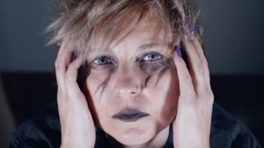 Melancholic woman with black eye make-up looking