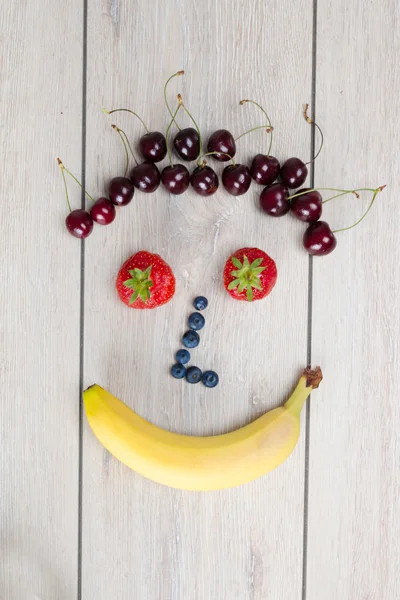 Schönes gesundes Gesicht mit reifen Früchten arrangiert — Stockfoto