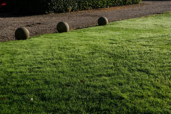 Gramado verde com três orbes de pedra ornamental atrás com caminho além — Fotografia de Stock