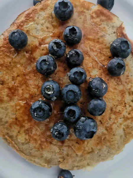 Bovenaanzicht van havermoutpannenkoek met bosbessen en besprenkeld met honing — Stockfoto