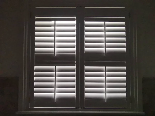 Full frame monochrome image of light shining through plantation shutters — Stock Photo, Image