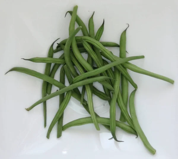 Pile of green french beans in plain white kitchen bowl. High quality photo