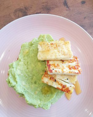 Tost üzerine kızarmış avokado, ızgara hallumi ve beyaz tabakta bal. Yüksek kalite fotoğraf