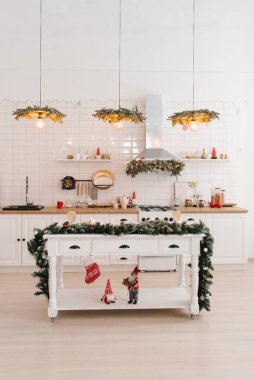 Yeni yıl ve Noel için dekore edilmiş İskandinav tarzı bir adada masası olan parlak bir mutfak.