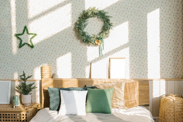 クリスマスと新年の作曲 明るいベッドリネンと明るい枕を持つ北欧の寝室 モミの枝の花輪とクリスマスの装飾 — ストック写真