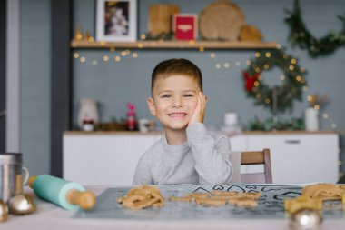 3-4 yaşlarında şirin bir çocuk masada oturuyor ve Noel kurabiyeleri hazırlıyor. Tatillerde evde aile tatili. Yeni Yıl ve Noel.
