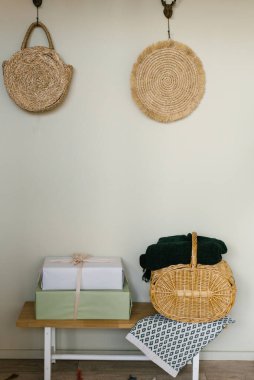İskandinav tarzında evin minimalist bir parçası. Hediye kutuları ve bej duvarın yanında hasır sepeti olan ahşap dükkan.