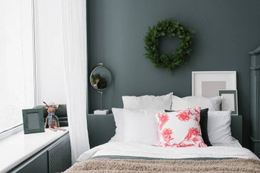 Şık bir Noel odası. Yatakta yastıklar ve duvarda bir çelenk