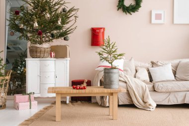 Oturma odasındaki Noel dekoru: kanepe, Noel ağacı, kahve masası, ince bej tonlu hediyeler.