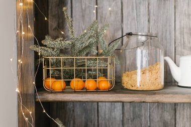 Mandallı ve köknar dallı bir sepet mutfak gereçleriyle dolu bir raftadır. Noel evi dekorasyonu
