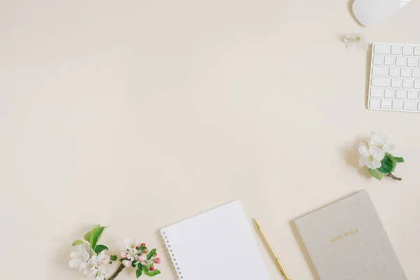 ブロガーやフリーランスの職場 ペン付きのメモ帳 空白の白いシート キーボードとマウス ベージュのテーブルの上に白いリンゴの花を開いたノートブック コピースペース 平置き — ストック写真