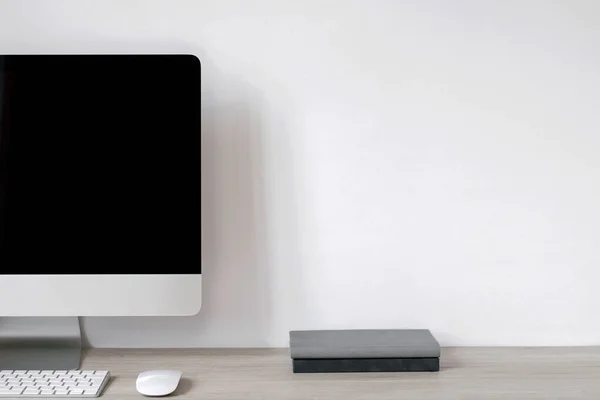 Laptop Czarnym Czystym Ekranem Notatnikami Stoi Stole Tle Białej Ściany — Zdjęcie stockowe