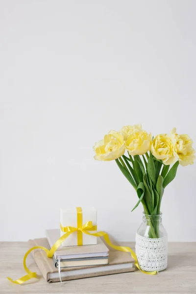 明るい黄色の花の花束とノートや本のスタックを職場で弓とギフトボックス ビジネスの女性のための花 同僚への贈り物 — ストック写真