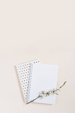 Bej arkaplan üzerinde beyaz elma çiçekleri olan boş bir defter kağıdı.