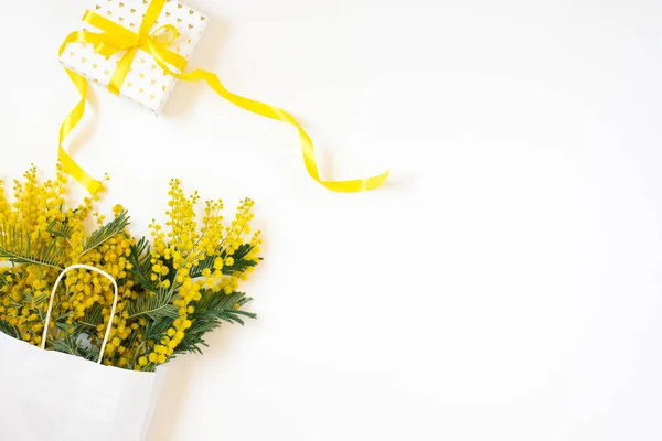 パッケージと現在の組成を持つ美しい花 枝花は白い背景にミモザを咲かせます バレンタインデーイースター誕生日母の日 フラットレイアウト トップビュー コピースペース — ストック写真