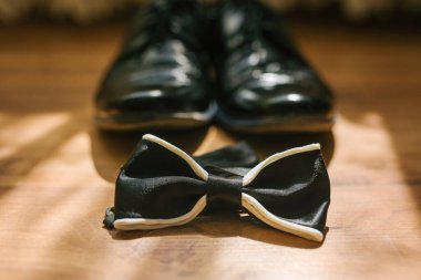 Damadın erkek ayakkabısının arka planında siyah papyon var.