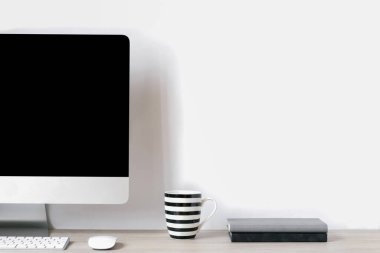 Teknoloji ve uzaktan çalışma konsepti. Masasında bilgisayar, bardak ve not defterleri olan yakışıklı metin yazarları işyerinin ön görüntüsü