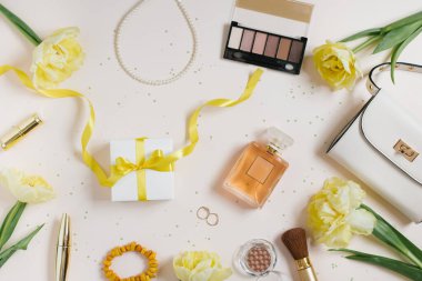 El çantalı, bahar çiçekli, sarı laleli, kozmetik ürünlü, aksesuarlı ve hediyeli blog yazarı bir kadın için aksesuar. Bahar işyeri konsepti. Düz yatıyordu.