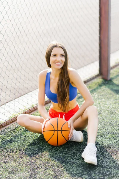 Seorang Gadis Cantik Fit Duduk Dengan Bola Basket Lapangan Olahraga — Stok Foto