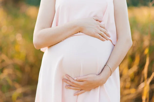 Eine Schwangere Frau Einem Rosafarbenen Kleid Hält Ihre Hände Auf — Stockfoto