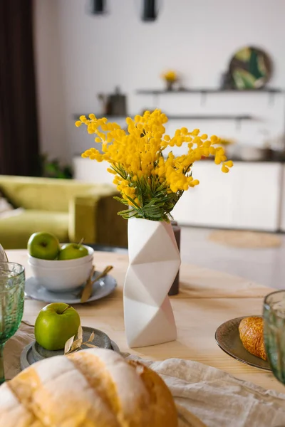 キッチンでお祝いや家のテーブルを提供する装飾のセラミック幾何学的な花瓶で明るい春のミモザ ストック写真