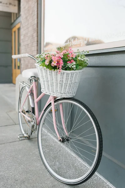 街のカフェの近くに花のバスケットを持つ装飾的な自転車 ロイヤリティフリーのストック画像