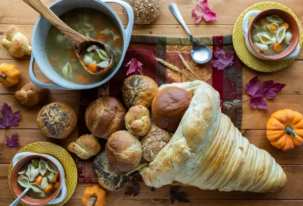 Kommen kalkoensoep en een zelfgemaakte cornucopia gemaakt van brood gevuld met broodjes. — Stockfoto