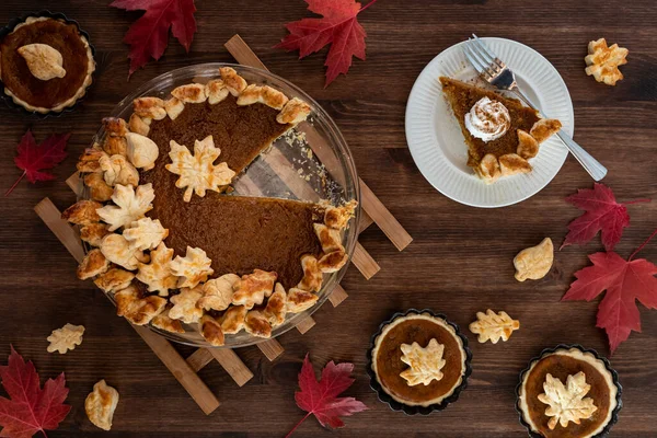 Top down view of a decorated homemade pumpkin pie with one slice on a plate. — Stock Photo, Image