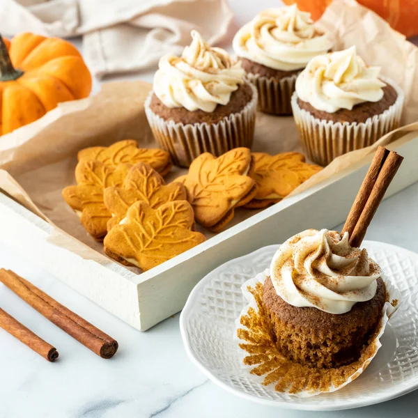 Un plateau de biscuits aux épices à la citrouille et de cupcakes avec un cupcake devant. — Photo