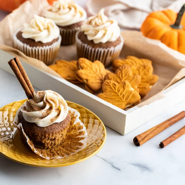Una bandeja de galletas de especias de calabaza y cupcakes con uno en el frente listo para comer. — Foto de Stock