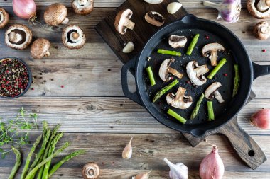 Dökme demir tavada taze kesilmiş kuşkonmaz ve mantar..