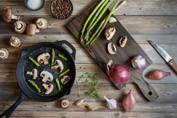 Mantar dilimleri ve kuşkonmaz ile pişirmeye hazır demir tava..