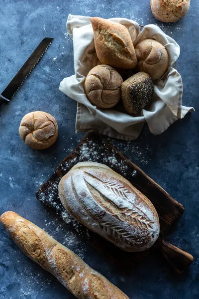 Visão de cima para baixo de vários pães de massa e pães contra um fundo escuro. — Fotografia de Stock