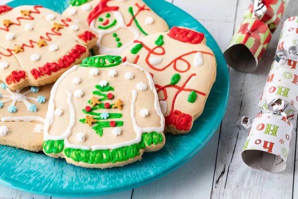 A plate of ugly Christmas sweater cookies with festive crackers to the right. — Stock Photo, Image