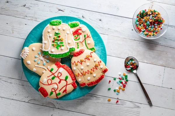 A plate of ugly Christmas sweater cookies with a bowl of sprinkles to the side. — Stock Photo, Image