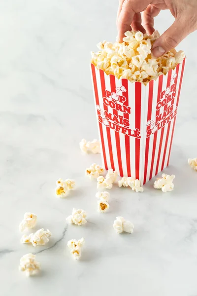 Jemand holt eine Handvoll Popcorn aus einem Popcornkarton. — Stockfoto