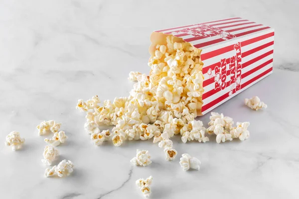 Ein Container Popcorn kippte vor hellem Hintergrund um. — Stockfoto