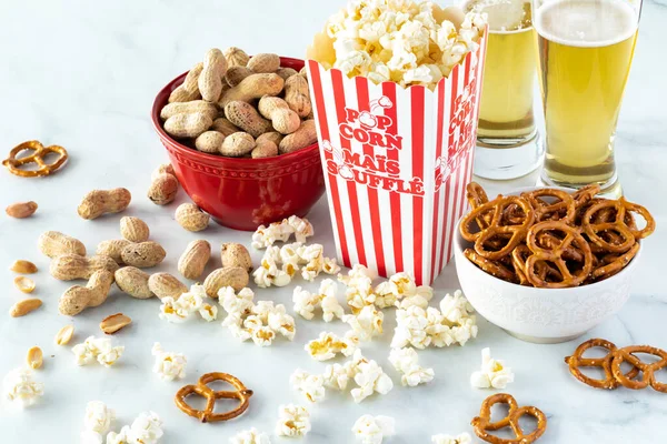 Erdnüsse, Popcorn und Brezeln mit Bier zum Naschen. — Stockfoto