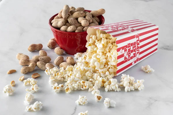 Nahaufnahme eines Behälters mit Popcorn, in dem eine Schüssel Erdnüsse steckt. — Stockfoto
