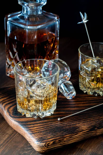 Vasos de whisky con hielo y una jarra llena de whisky detrás. —  Fotos de Stock