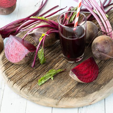 Bir bardak pancar suyu ve etrafını saran pancar pancarının yakın görüntüsü..