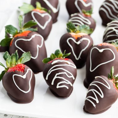 Several decorated chocolate covered strawberries on a plate. 