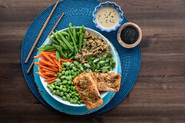 Vista de arriba hacia abajo de una ensaladera de salmón asiático con coberturas en una mesa de madera. — Foto de Stock