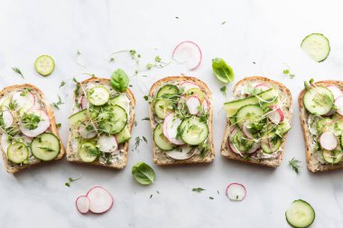 Bir sıra açık salatalık ve turplu sandviçin yukarıdan görünüşü. 