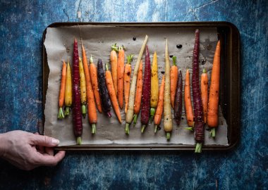 Kavrulmuş gökkuşağı havuçlu fırın örtüsü, mavi arka planda..