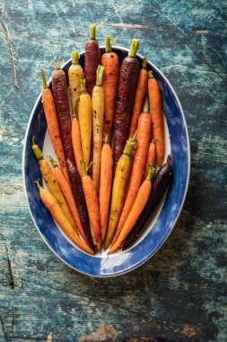 Kavrulmuş gökkuşağı havuçlarıyla dolu oval servis tabağının yukarıdan görünüşü.