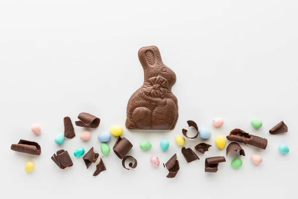 Шоколадный пасхальный кролик с шоколадной стружкой и яичницей пастельного цвета. — стоковое фото