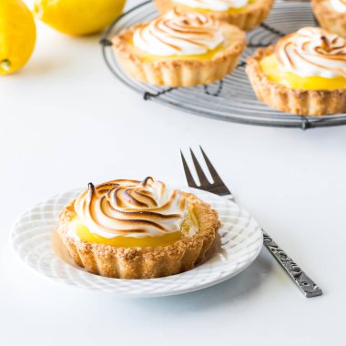 Bir porsiyon limonlu tart ve arkasında daha fazlası olan soğutma rafı..