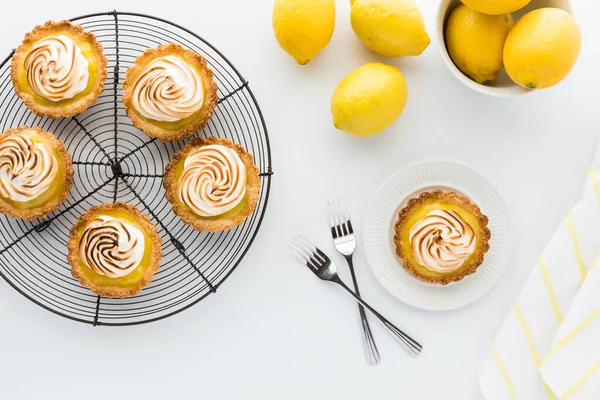 Un rack de tartelettes au citron meringue avec une portion prête à manger. — Photo