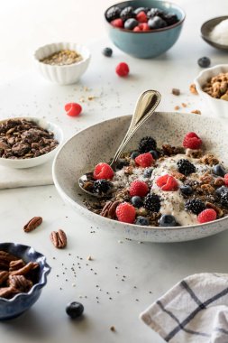 Bir kase yulaf yoğurdu, meyveli, fındıklı ve çekirdekli sos..
